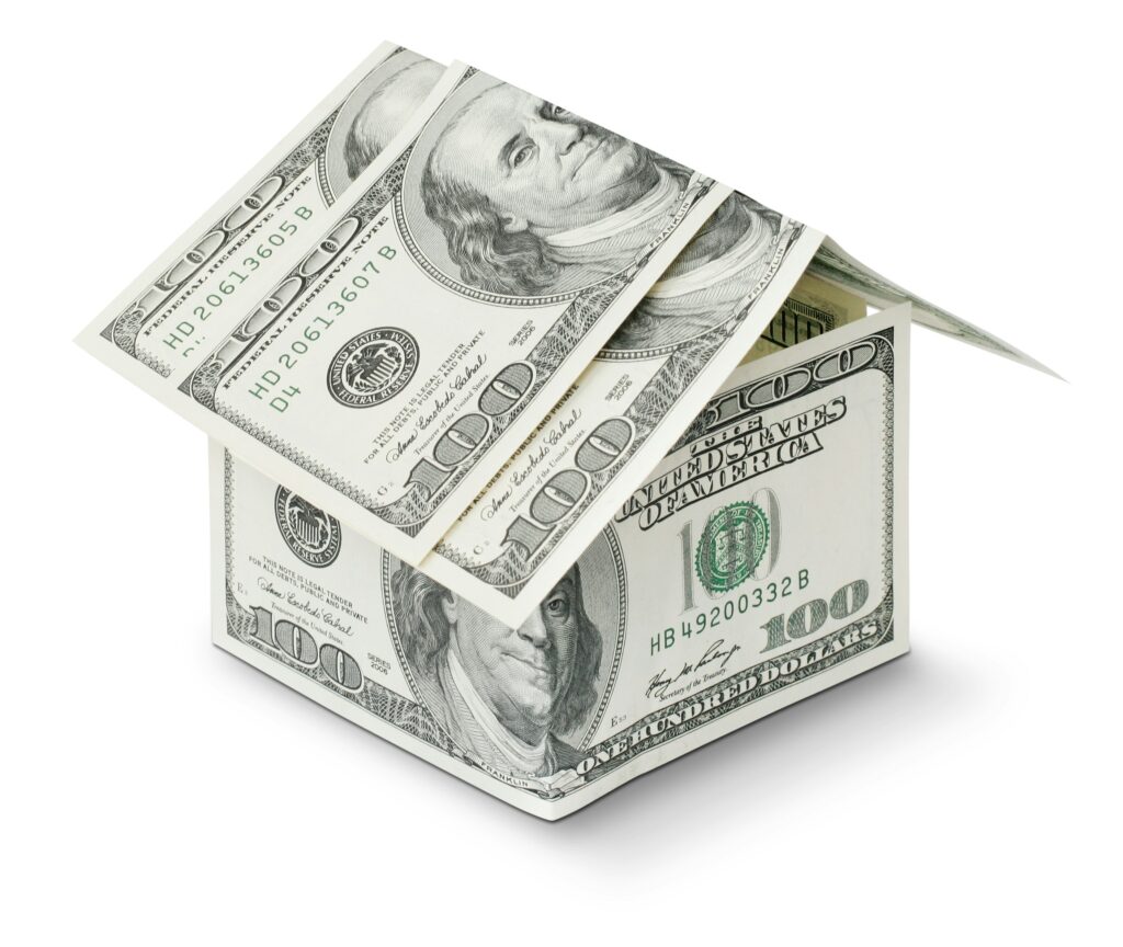 Real success represented by a tiny home made from $100 bills.